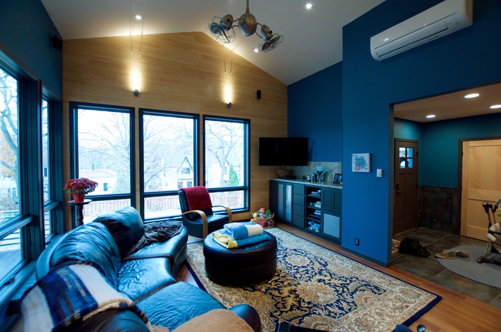 Cette image montre une salle de séjour design ouverte avec un mur bleu, parquet clair et un sol marron.