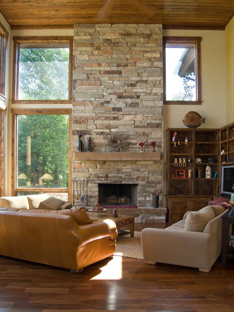 Ejemplo de sala de estar abierta rural grande con paredes amarillas, suelo de madera oscura, todas las chimeneas, marco de chimenea de piedra y pared multimedia