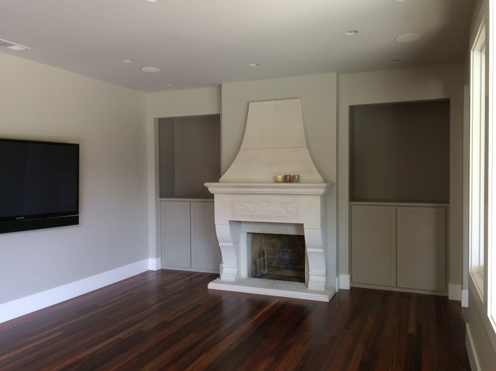 Пример оригинального дизайна: изолированная гостиная комната среднего размера в стиле неоклассика (современная классика) с серыми стенами, темным паркетным полом, стандартным камином, фасадом камина из штукатурки, телевизором на стене и коричневым полом