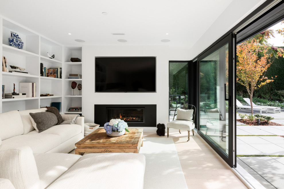 Bild på ett allrum med öppen planlösning, med vita väggar, ljust trägolv, en standard öppen spis, en väggmonterad TV och beiget golv