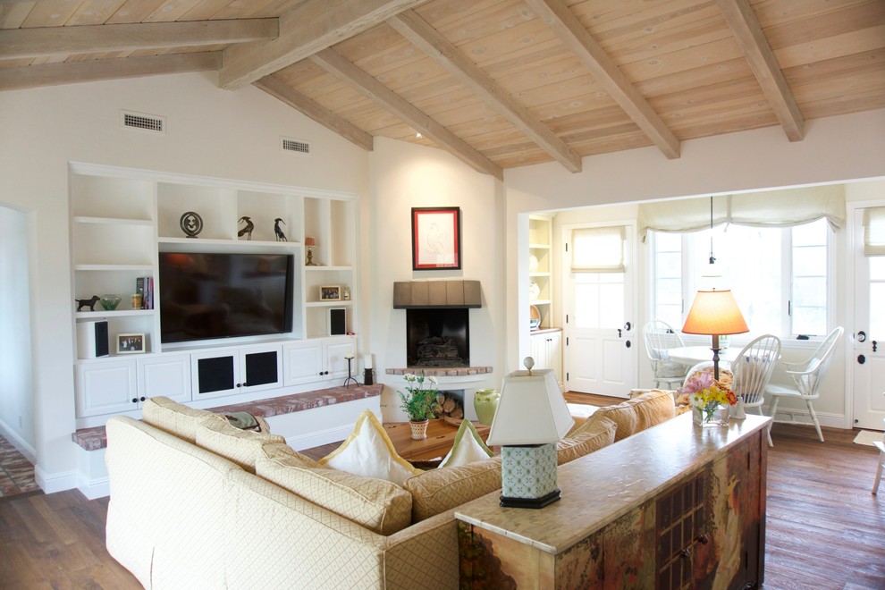 Offenes Landhausstil Wohnzimmer mit weißer Wandfarbe, dunklem Holzboden, Eckkamin, verputzter Kaminumrandung und Multimediawand in San Diego