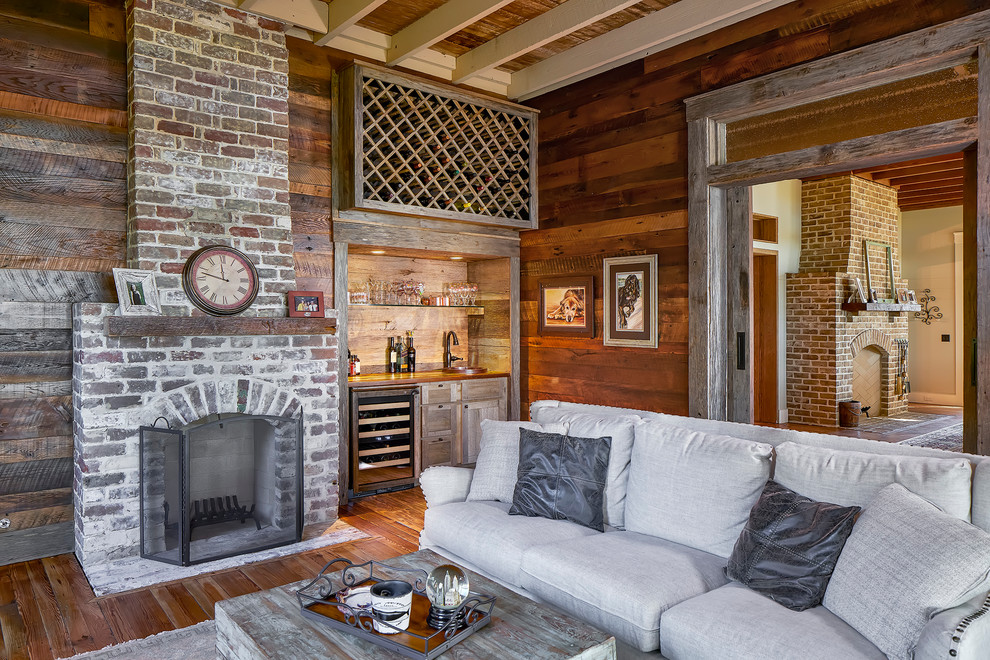 Abgetrenntes Country Wohnzimmer mit Hausbar, braunem Holzboden, Kamin und Kaminumrandung aus Backstein in Atlanta
