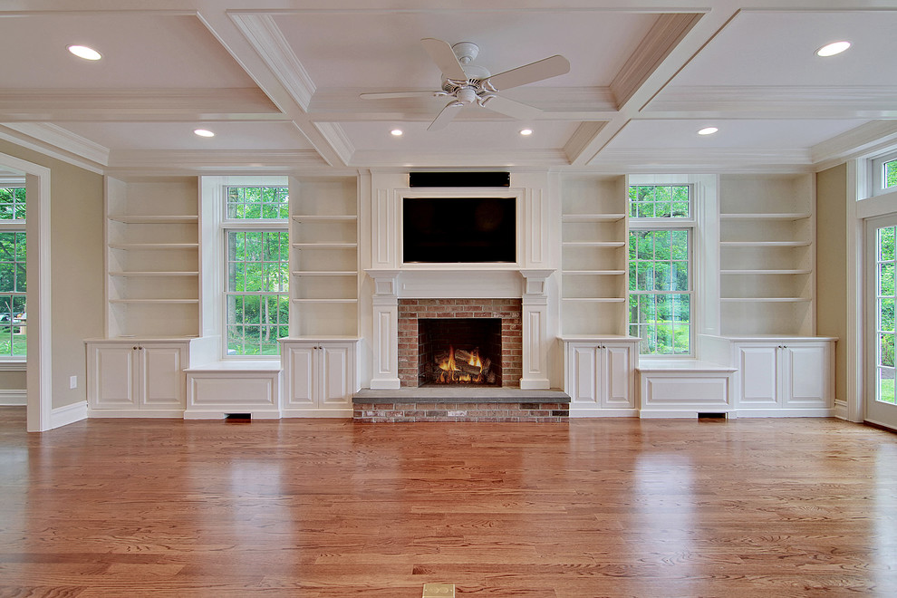 This is an example of a large traditional enclosed games room in New York with beige walls, dark hardwood flooring, a standard fireplace, a brick fireplace surround, a wall mounted tv and brown floors.