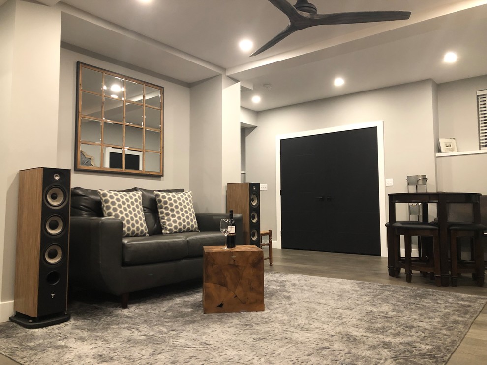Modelo de sala de estar con barra de bar abierta clásica renovada de tamaño medio sin chimenea con paredes grises, suelo de madera en tonos medios y suelo gris