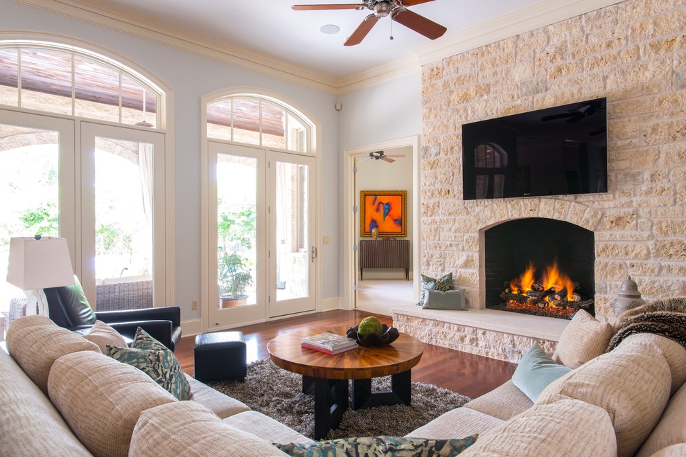 Mid-sized transitional open concept medium tone wood floor family room photo in Austin with a standard fireplace, a stone fireplace and a wall-mounted tv