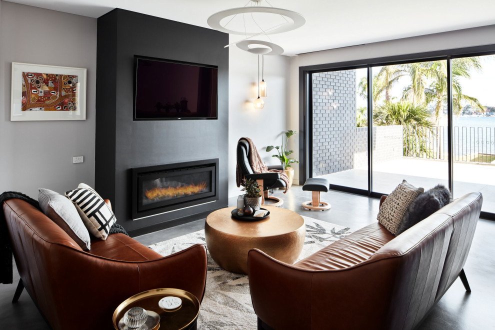 Cette image montre une salle de séjour design avec un mur gris, sol en béton ciré, une cheminée ribbon, un téléviseur fixé au mur et un sol gris.