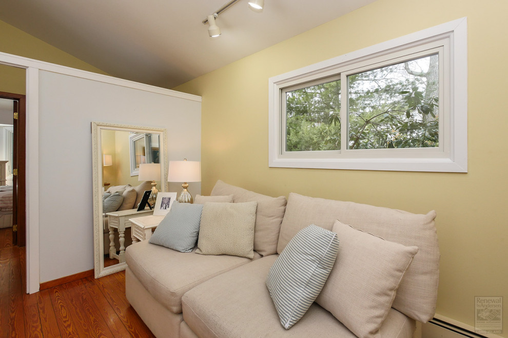 Foto di un piccolo soggiorno aperto con libreria, pareti gialle, pavimento in legno massello medio, nessuna TV e soffitto a volta