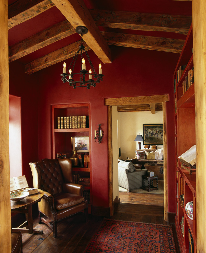 Cette image montre une salle de séjour sud-ouest américain avec un mur rouge et parquet foncé.