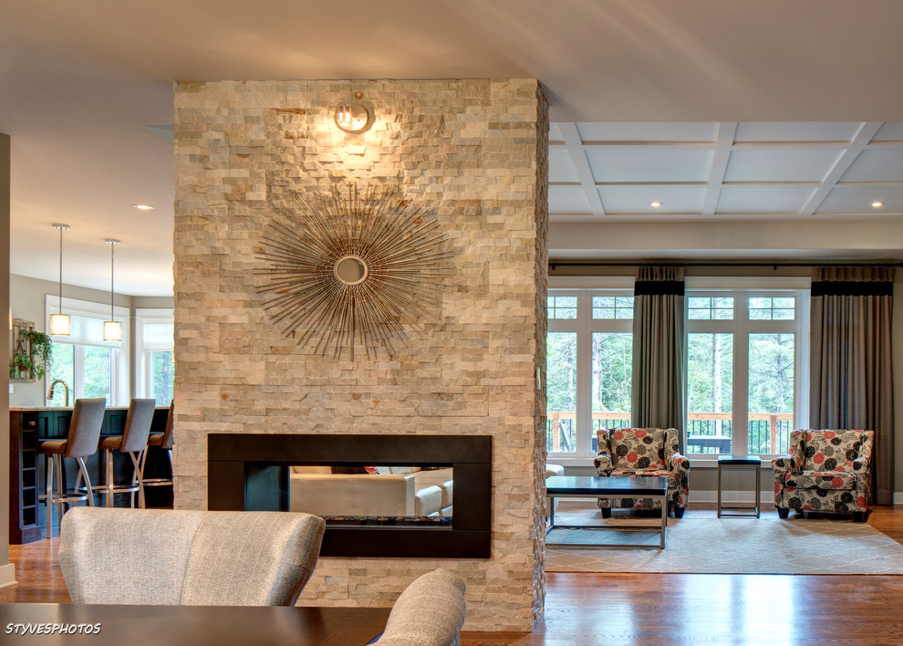 Foto de sala de estar clásica renovada con chimenea de doble cara y marco de chimenea de piedra