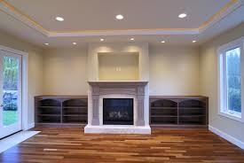Modelo de sala de estar abierta clásica de tamaño medio con paredes beige, suelo de madera en tonos medios, todas las chimeneas y marco de chimenea de madera