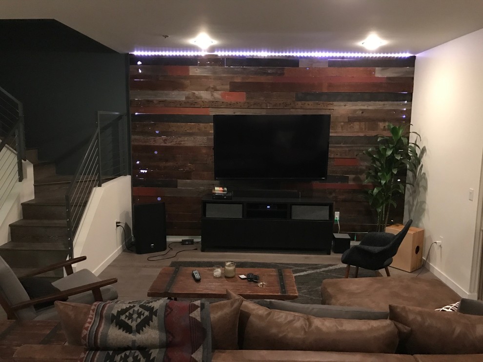 Diseño de sala de estar abierta rural pequeña sin chimenea con paredes marrones, suelo de madera clara, televisor colgado en la pared y suelo gris