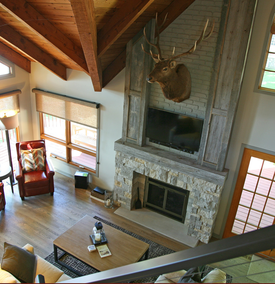 This is an example of a medium sized urban open plan games room in Milwaukee with grey walls, light hardwood flooring, a standard fireplace and a wooden fireplace surround.