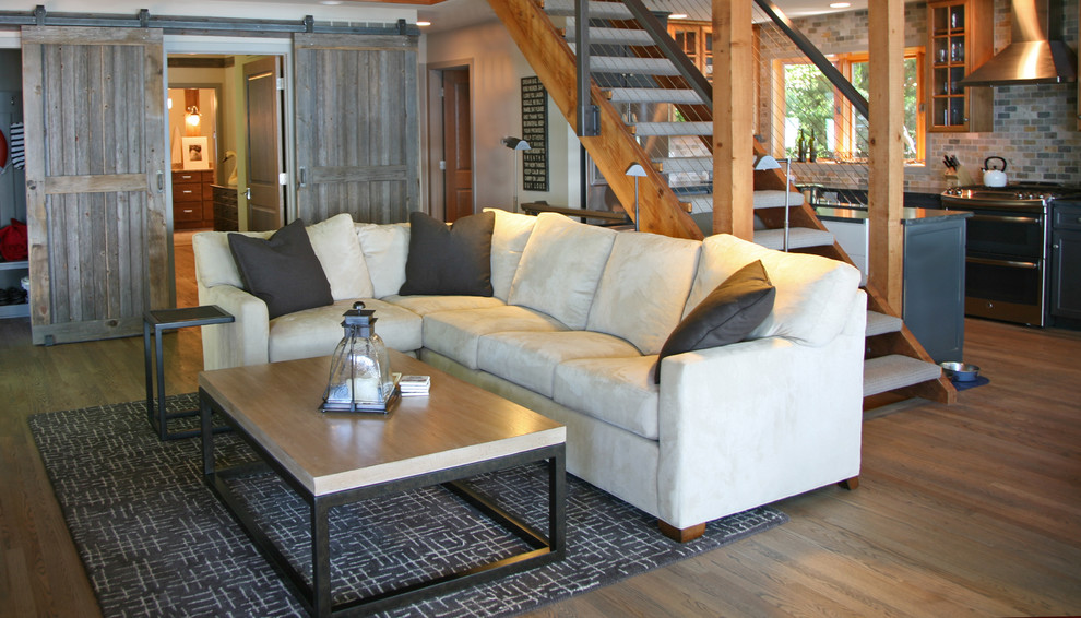 Modelo de sala de estar abierta urbana de tamaño medio con paredes grises, suelo de madera clara y televisor colgado en la pared