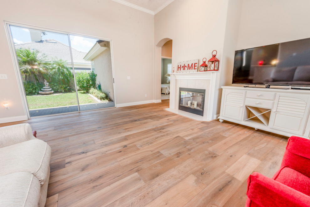 Photo of a large farmhouse open plan games room in Orlando with grey walls, light hardwood flooring, a standard fireplace, a tiled fireplace surround, a freestanding tv and beige floors.