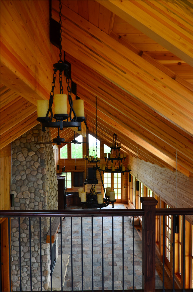 カルガリーにある高級な広いトラディショナルスタイルのおしゃれなオープンリビング (スレートの床、標準型暖炉、石材の暖炉まわり、マルチカラーの床) の写真