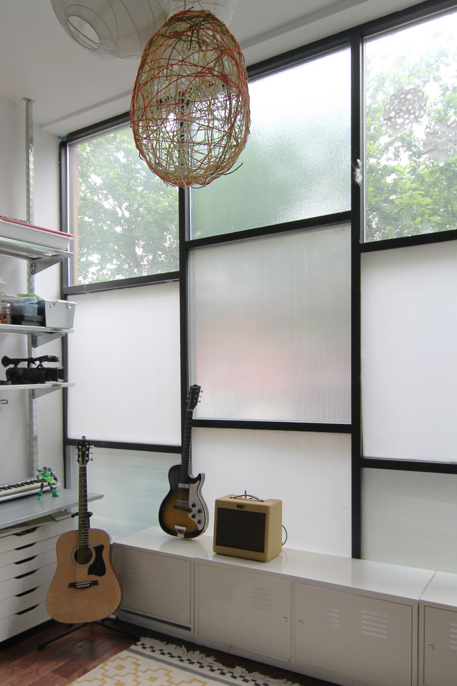 Modern inredning av ett mellanstort allrum, med vita väggar, mörkt trägolv och ett musikrum