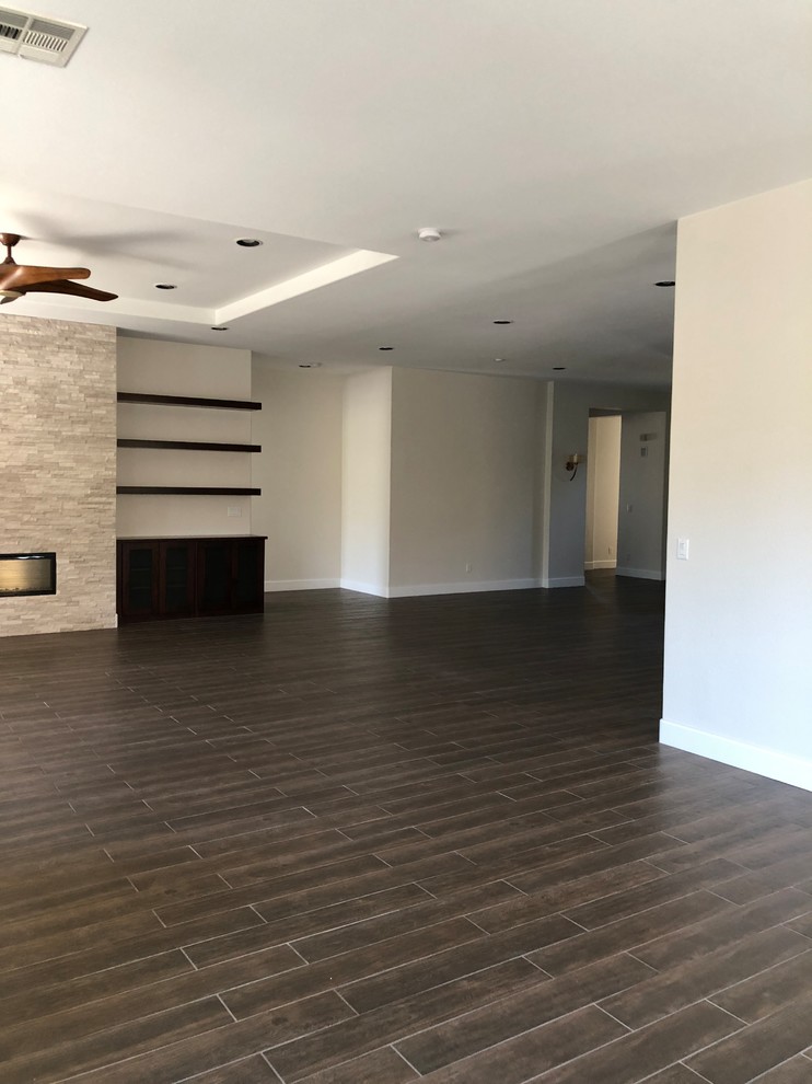 Large traditional open plan games room in Las Vegas with grey walls, porcelain flooring, a ribbon fireplace, a stone fireplace surround and brown floors.