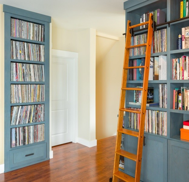 Idée de décoration pour une grande salle de séjour tradition ouverte avec une bibliothèque ou un coin lecture, un sol en bois brun et un mur jaune.