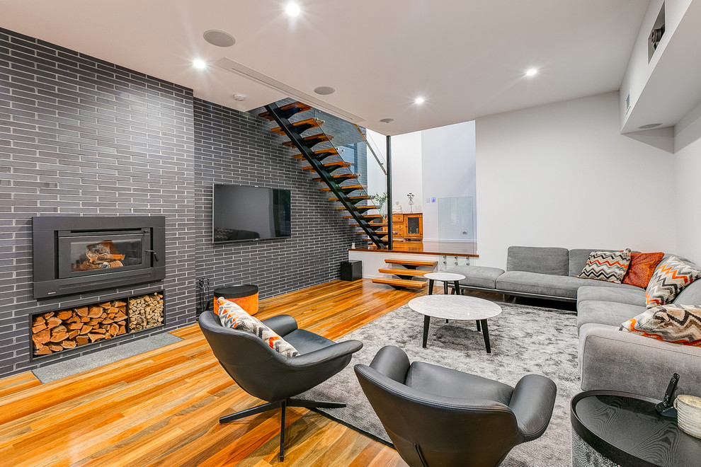 Mittelgroßes Modernes Wohnzimmer mit weißer Wandfarbe, braunem Holzboden, TV-Wand und Gaskamin in Brisbane