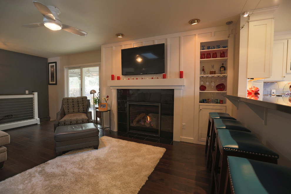 Modelo de sala de estar abierta de estilo americano de tamaño medio con paredes multicolor, todas las chimeneas, marco de chimenea de madera y televisor colgado en la pared