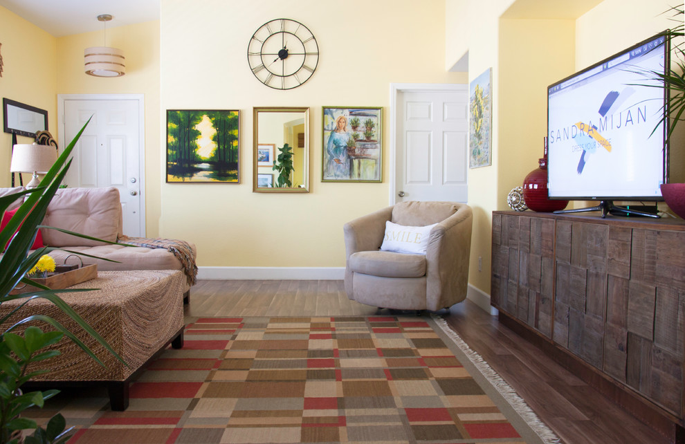 Foto di un grande soggiorno chic aperto con pareti gialle, pavimento in laminato, nessun camino, TV autoportante e pavimento marrone