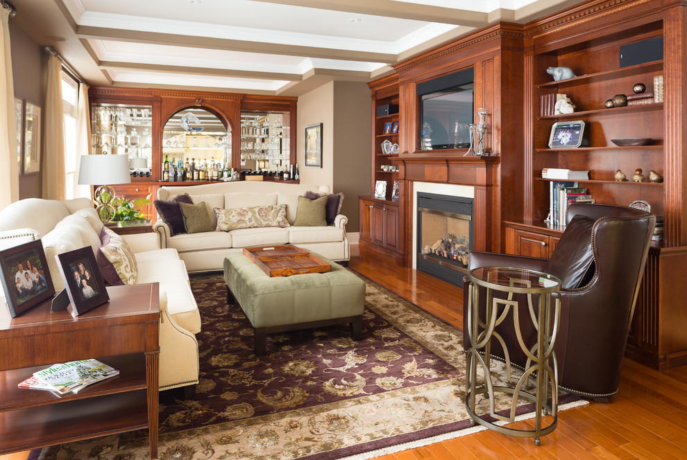 Inspiration for a mid-sized timeless medium tone wood floor family room remodel in Toronto with beige walls, a standard fireplace and a wall-mounted tv