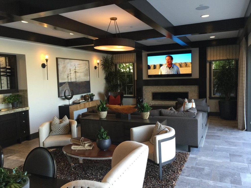 This is an example of a medium sized classic enclosed games room in Orange County with a home bar, beige walls, no fireplace, a wall mounted tv, ceramic flooring, a stone fireplace surround and grey floors.