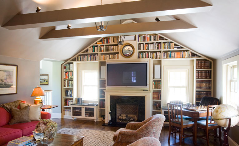 Esempio di un soggiorno tradizionale con libreria, pareti beige, pavimento in legno massello medio, camino classico e TV a parete