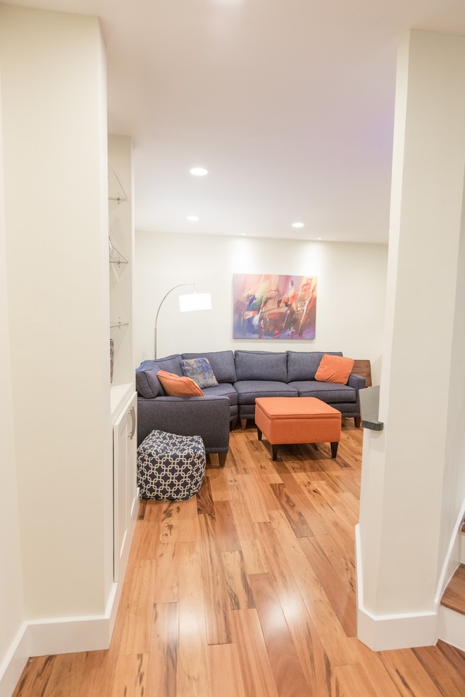 Imagen de sala de estar contemporánea pequeña sin chimenea con paredes blancas, suelo de madera en tonos medios y televisor colgado en la pared