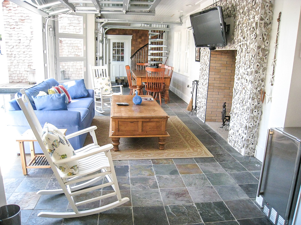 Пример оригинального дизайна: большая открытая гостиная комната в морском стиле с белыми стенами, полом из сланца, стандартным камином, телевизором на стене и разноцветным полом