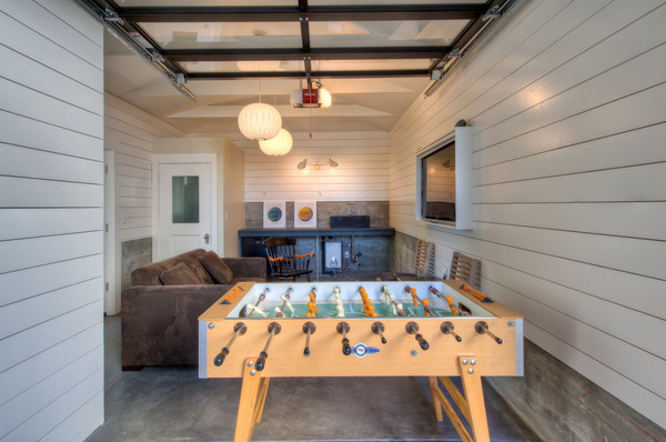 Large contemporary mezzanine games room in San Francisco with a game room, white walls, a concealed tv and concrete flooring.