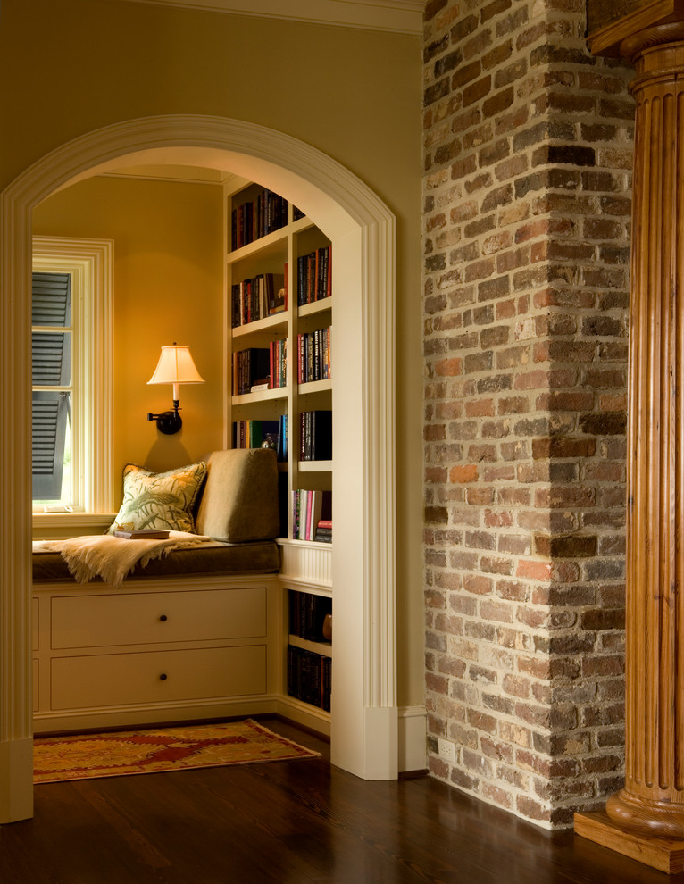 Cette image montre une petite salle de séjour traditionnelle fermée avec une bibliothèque ou un coin lecture, un mur beige et parquet foncé.