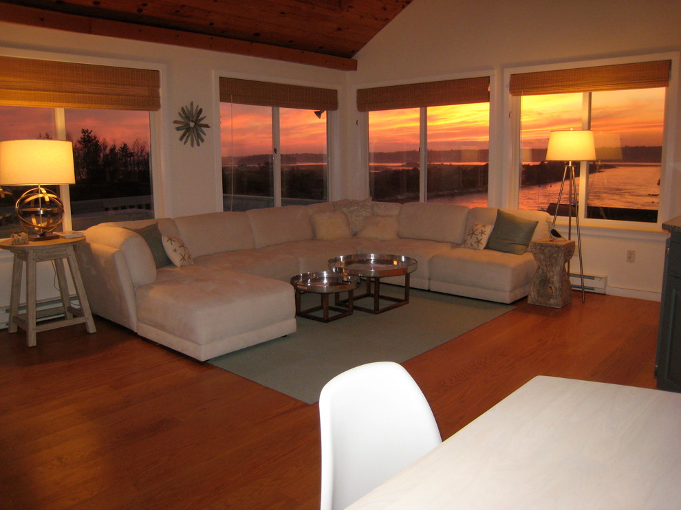 Modelo de sala de estar abierta costera de tamaño medio con paredes beige, suelo de madera en tonos medios y suelo marrón