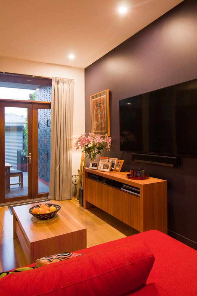 Diseño de sala de estar contemporánea pequeña con paredes púrpuras, suelo de madera clara, televisor colgado en la pared y suelo marrón