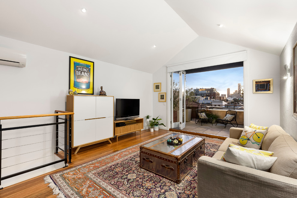 Mittelgroßes Modernes Wohnzimmer ohne Kamin, im Loft-Stil mit weißer Wandfarbe, braunem Holzboden und freistehendem TV in Melbourne