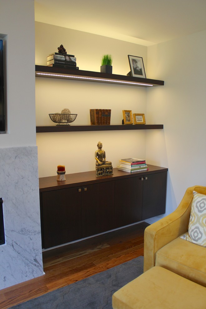 Imagen de sala de estar abierta moderna de tamaño medio con paredes grises, suelo de madera en tonos medios, chimenea lineal, marco de chimenea de piedra y pared multimedia