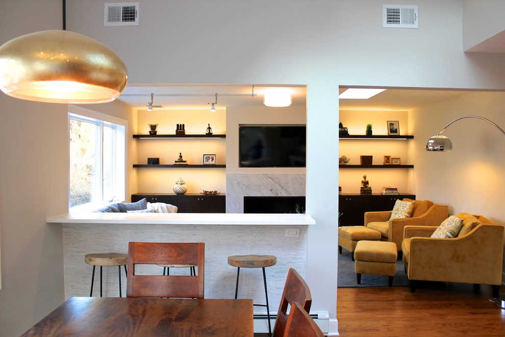 Foto de sala de estar abierta moderna de tamaño medio con paredes grises, suelo de madera en tonos medios, chimenea lineal, marco de chimenea de piedra y pared multimedia