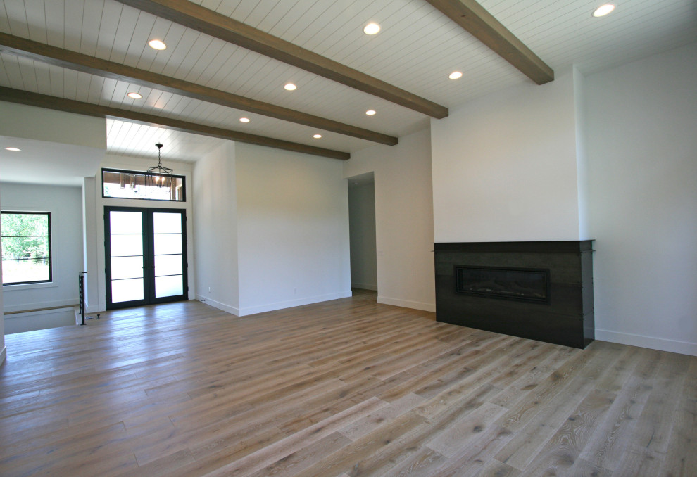 シアトルにある高級な広いトランジショナルスタイルのおしゃれなオープンリビング (白い壁、無垢フローリング、横長型暖炉、金属の暖炉まわり、壁掛け型テレビ、ベージュの床、塗装板張りの天井) の写真