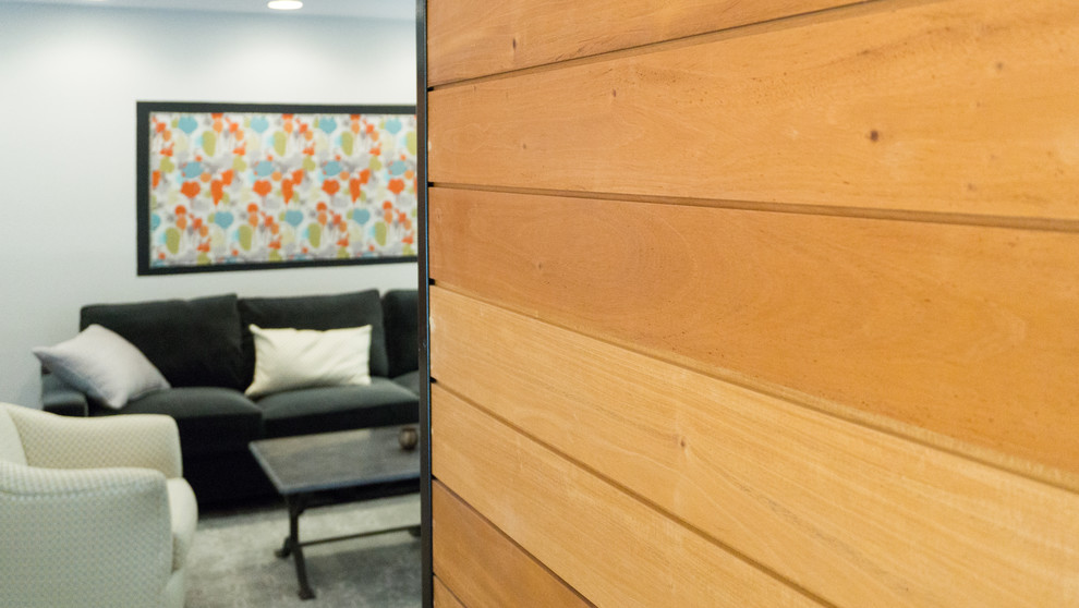 Mittelgroßes, Offenes Modernes Wohnzimmer mit grauer Wandfarbe, braunem Holzboden, Kamin, gefliester Kaminumrandung und TV-Wand in Austin