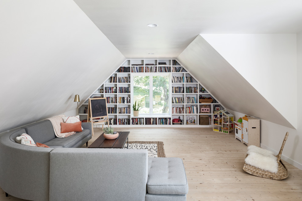Lantlig inredning av ett mellanstort allrum med öppen planlösning, med vita väggar, ljust trägolv, ett bibliotek och beiget golv