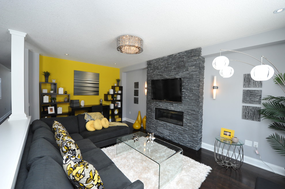 Photo of a medium sized modern open plan games room in Toronto with grey walls, dark hardwood flooring, a standard fireplace, a stone fireplace surround, a wall mounted tv and brown floors.