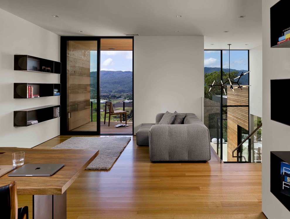 Imagen de sala de estar actual con paredes blancas, suelo de madera en tonos medios y suelo marrón