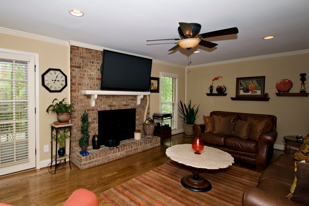 This is an example of a medium sized traditional open plan games room in Atlanta with beige walls, medium hardwood flooring, a standard fireplace, a brick fireplace surround and a wall mounted tv.