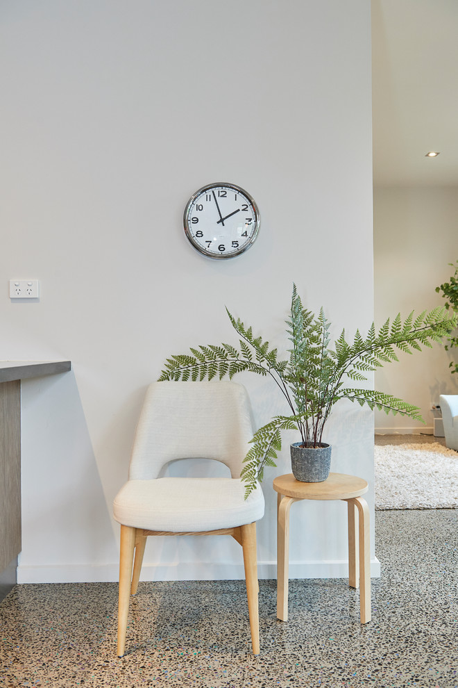 This is an example of a medium sized scandinavian open plan games room in Melbourne with white walls, concrete flooring, no fireplace, a wall mounted tv and grey floors.