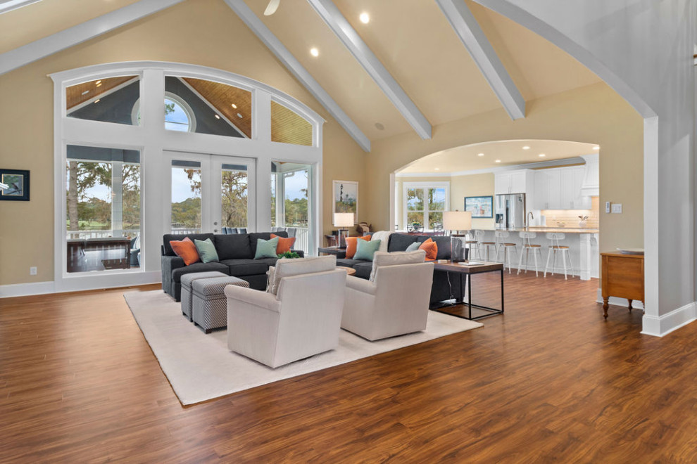Large beach style open concept vinyl floor, brown floor, vaulted ceiling and shiplap wall family room photo in Raleigh with yellow walls, a standard fireplace, a tile fireplace and a wall-mounted tv