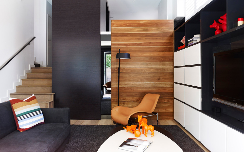 Modelo de salón abierto actual sin chimenea con paredes multicolor, suelo de madera clara, pared multimedia y alfombra