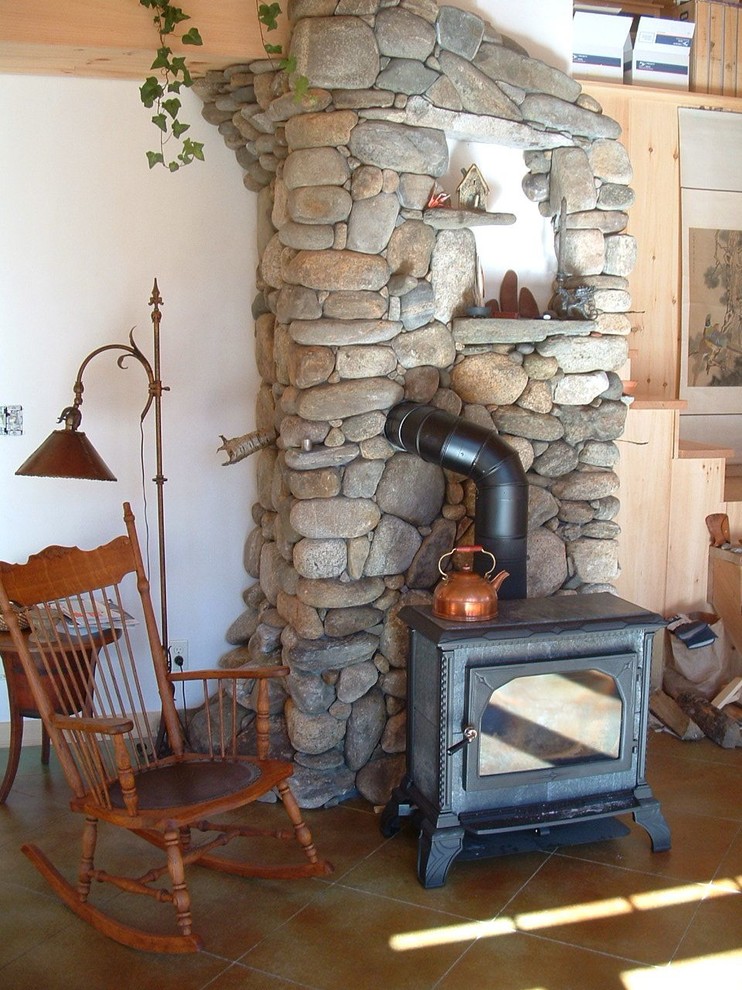 Imagen de sala de estar rústica con marco de chimenea de piedra