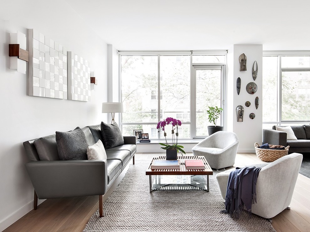 Imagen de sala de estar abierta actual con paredes blancas, suelo de madera clara y pared multimedia