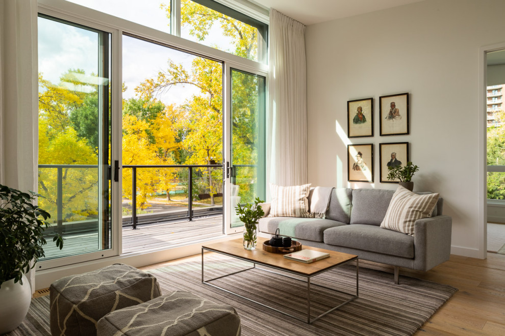 Mittelgroßes, Offenes Modernes Wohnzimmer mit weißer Wandfarbe, hellem Holzboden, TV-Wand und beigem Boden in Calgary