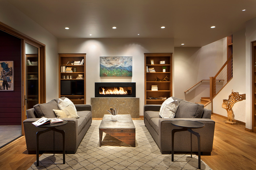 Photo of a large traditional open plan games room in Other with a game room, white walls, medium hardwood flooring, a ribbon fireplace, a metal fireplace surround and a built-in media unit.